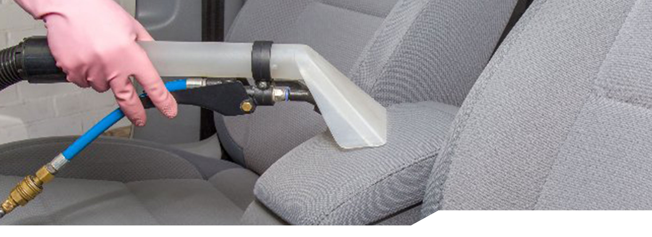 Technician using a vacuum to detail the interior of a car