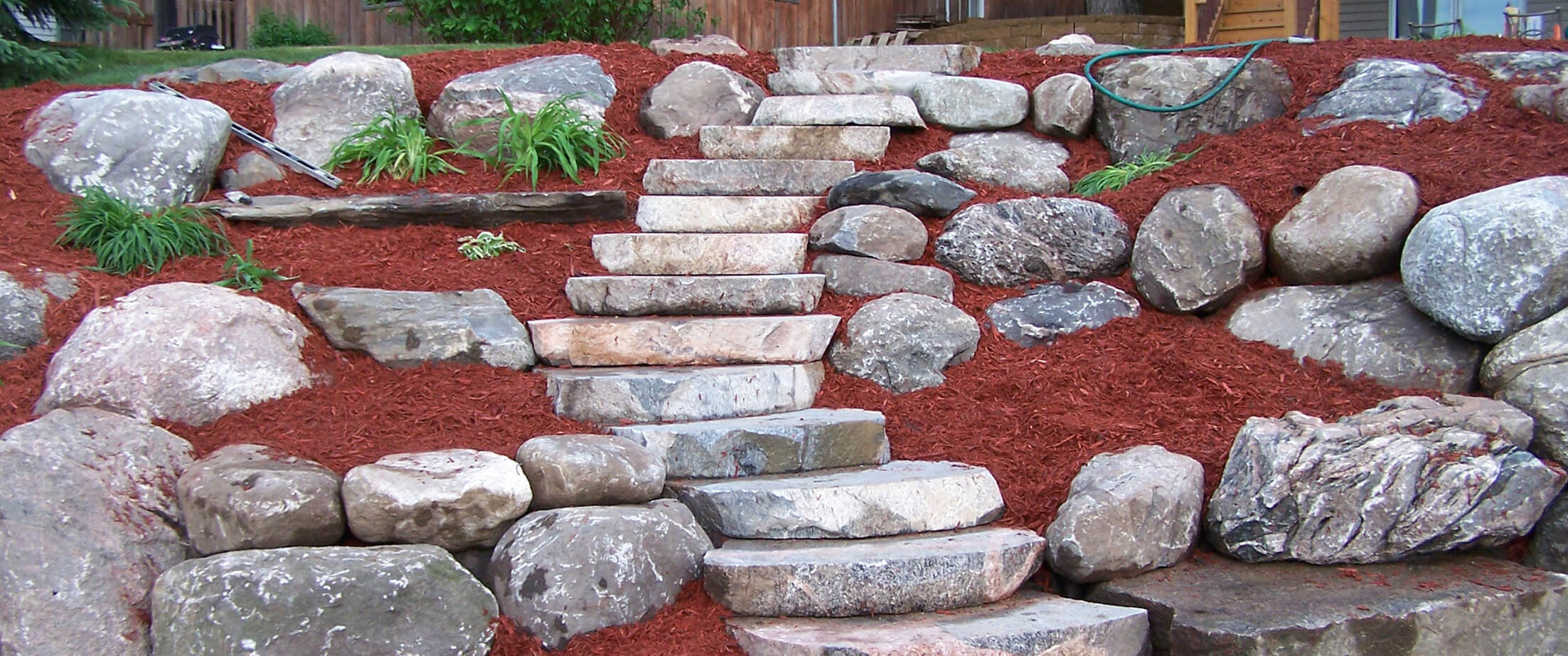 Boulder retaining wall with cut boulder steps